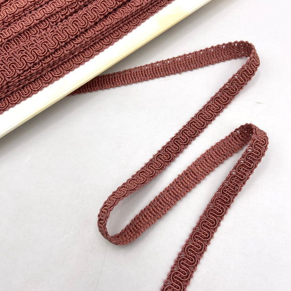 Mauve trim made from braided and twisted cords that form a snaking design.