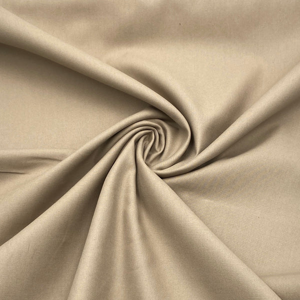 A khaki-colored twill weave fabric scrunched in the middle to show how the fabric folds and moves. 