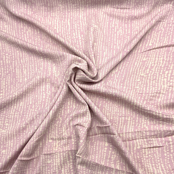 A close-up of light mauve fabric with a crinkle texture and speckled stripe design.