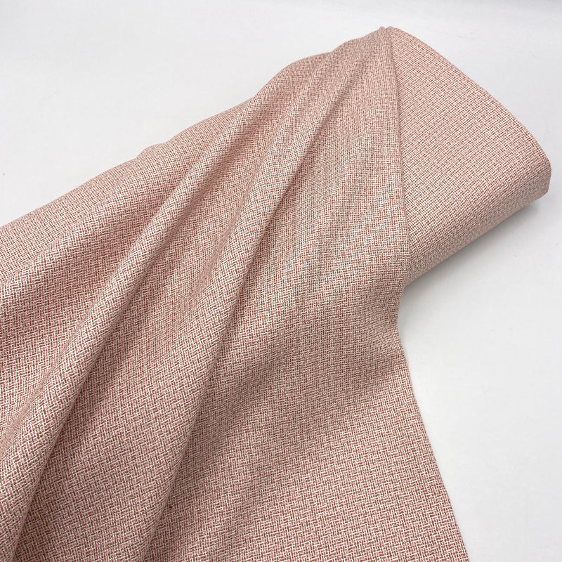 A bolt of pink suiting fabric on a white table.