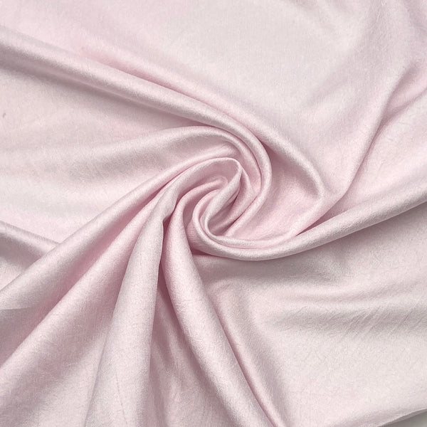 A close-up of a light pink fabric with a subtle crepe texture.