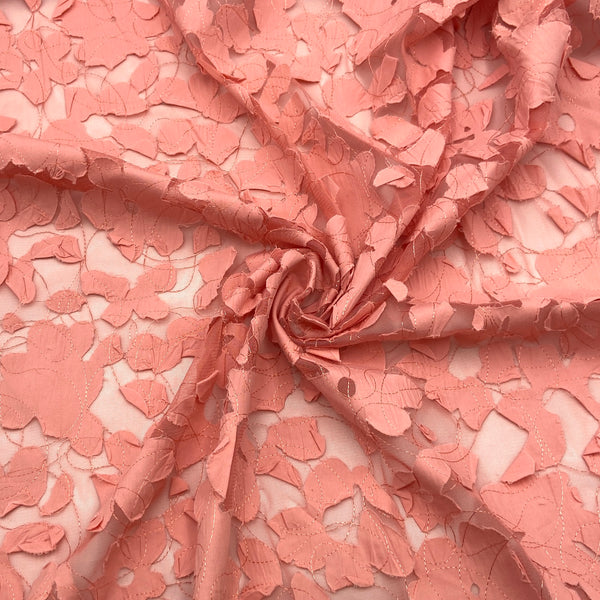 A warm coral-colored floral fabric with sheer portions and embroidery.