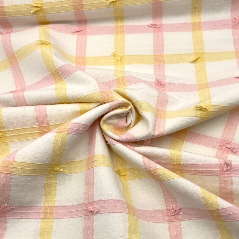 A white fabric with yellow and pink woven plaid stripes and decorative clipped threads. 