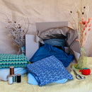 Fabric pieces and sewing supplies on a table with a cardboard box.