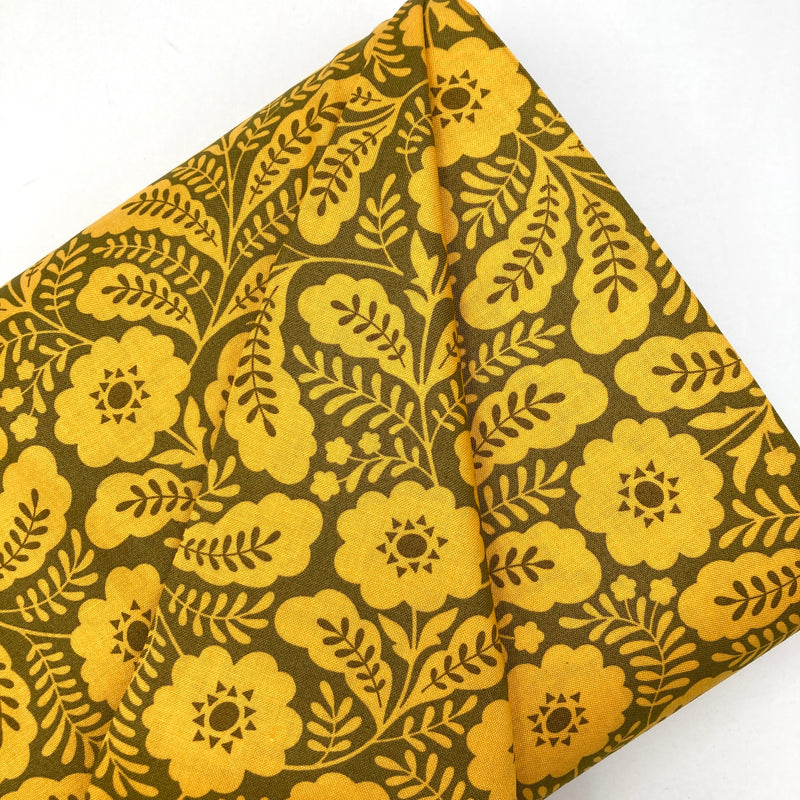 A dark olive green quilting cotton fabric with bold yellow geometric floral designs.