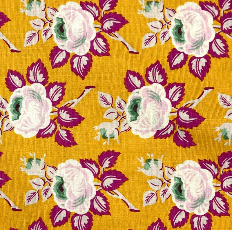 A 100% cotton quilting fabric with a bold white and fuschia floral design on a golden yellow background.