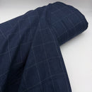 Roll of dark blue linen Italian deadstock fabric with a check pattern on a white background