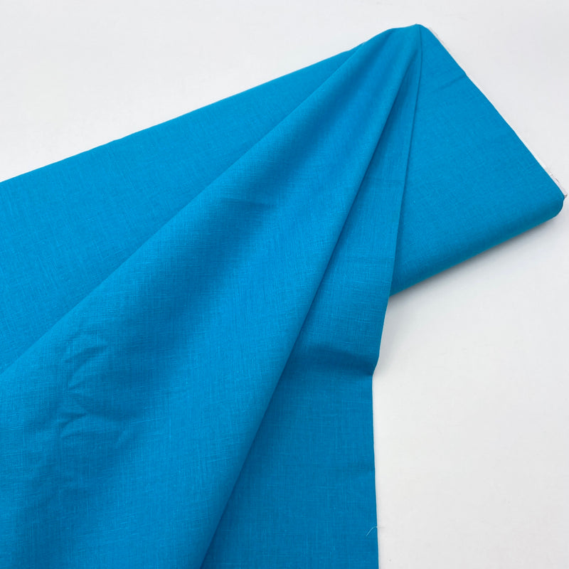 A bolt of bright blue fabric on a white table. 