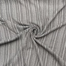 A close-up of grey striped fabric filling the frame but scrunched in the middle in a swirl.