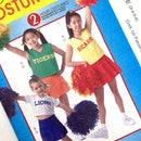 Image of kids modeling McCall's Costumes 4619 cheerleader costumes, featuring outfits with 'Tigers', 'Bears', and 'Lions' text on the green, yellow, and blue skirts, respectively. The children are holding pom-poms and wearing white tops.