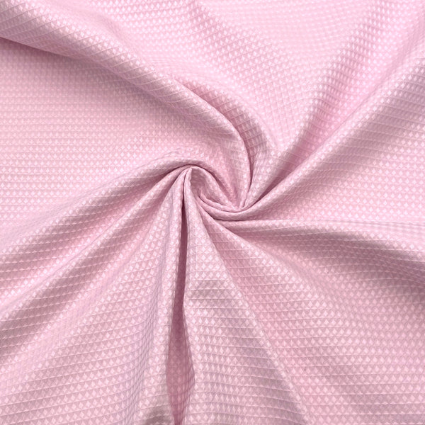 A close-up of waffle textured woven fabric in a light pink color. 