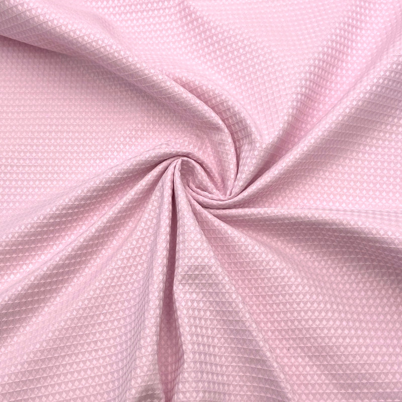 A close-up of waffle textured woven fabric in a light pink color. 