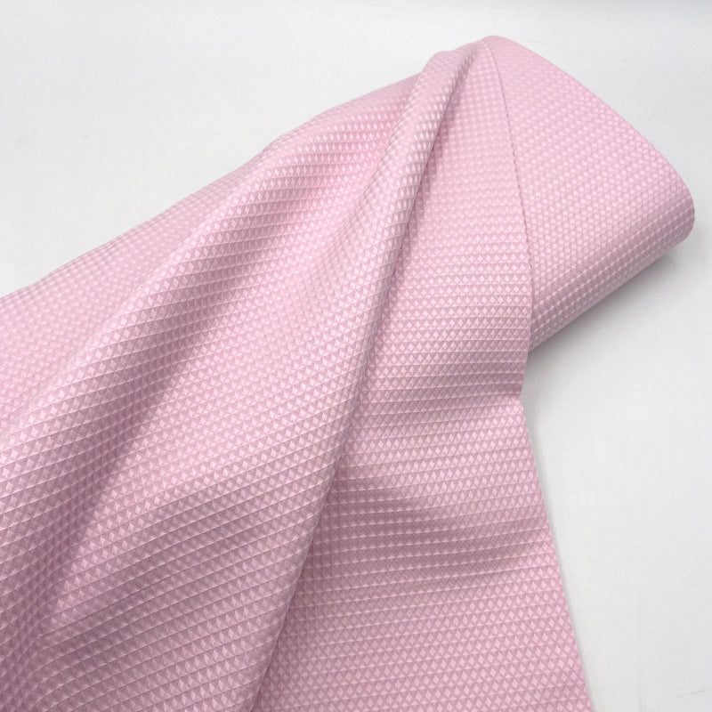 A bolt of light pink waffle weave cotton fabric. 