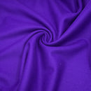 A close up of purple wool fabric scrunched in a swirl to show the texture of the fabric