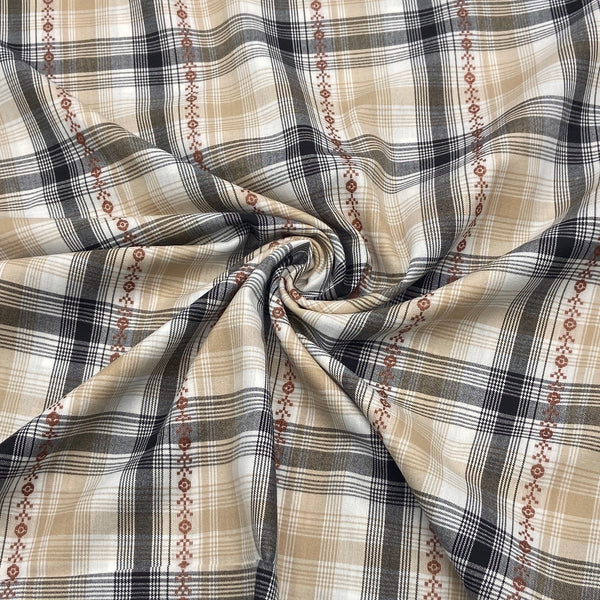 A close-up of white, black, and tan plaid fabric that is scrunched in the middle in a swirl to demonstrate the way the fabric folds and moves.