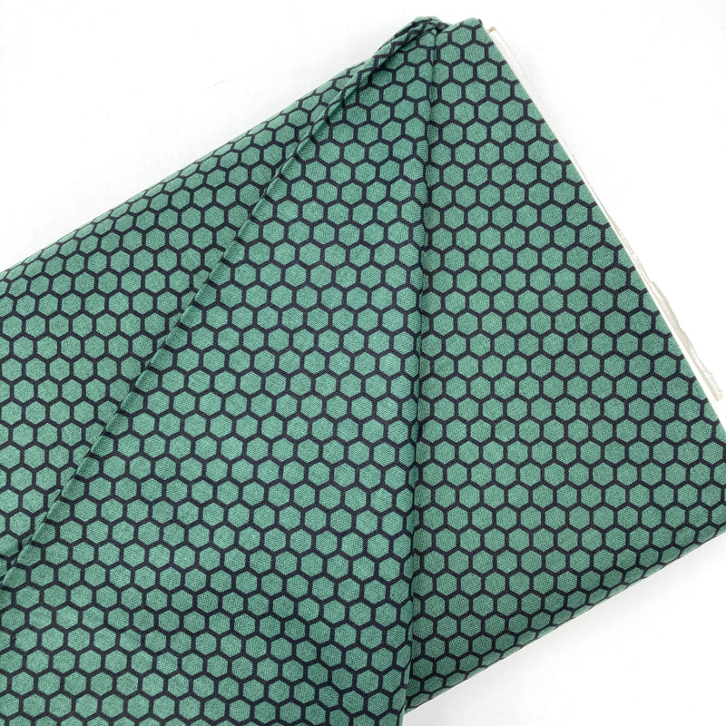 A bolt of quilting cotton with a black honeycomb outline design on a calming green background.