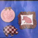 A set of three craft patterns featuring a pig and piglet design, with one pattern showing a pink pig plaque, another with a brown pig patchwork fabric, and a third showing a piglet in a checkered pattern. The background is a solid blue.