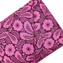A bolt of quilting cotton fabric with a geometric floral design in a lilac color on a darker purple background.