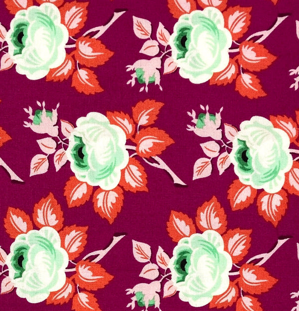 A 100% cotton quilting fabric featuring a soft green flower with red leaves on a magenta background.