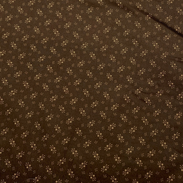 Cotton fabric with dot and star motifs in tan on a chocolate brown background.