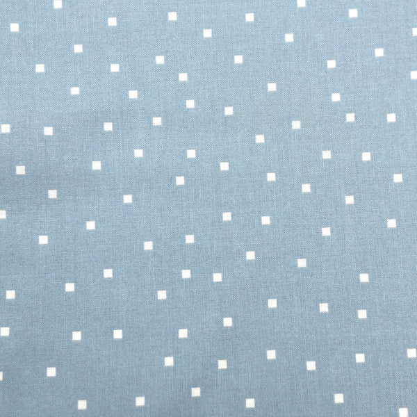 small white squares on a light blue background of quilting fabric
