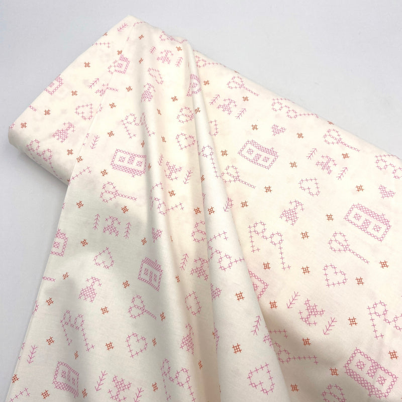 pink cross stitch print on white quilting fabric