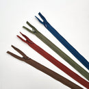 A collection of YKK invisible zippers in brown, green, and red colors, laid out on a white background.