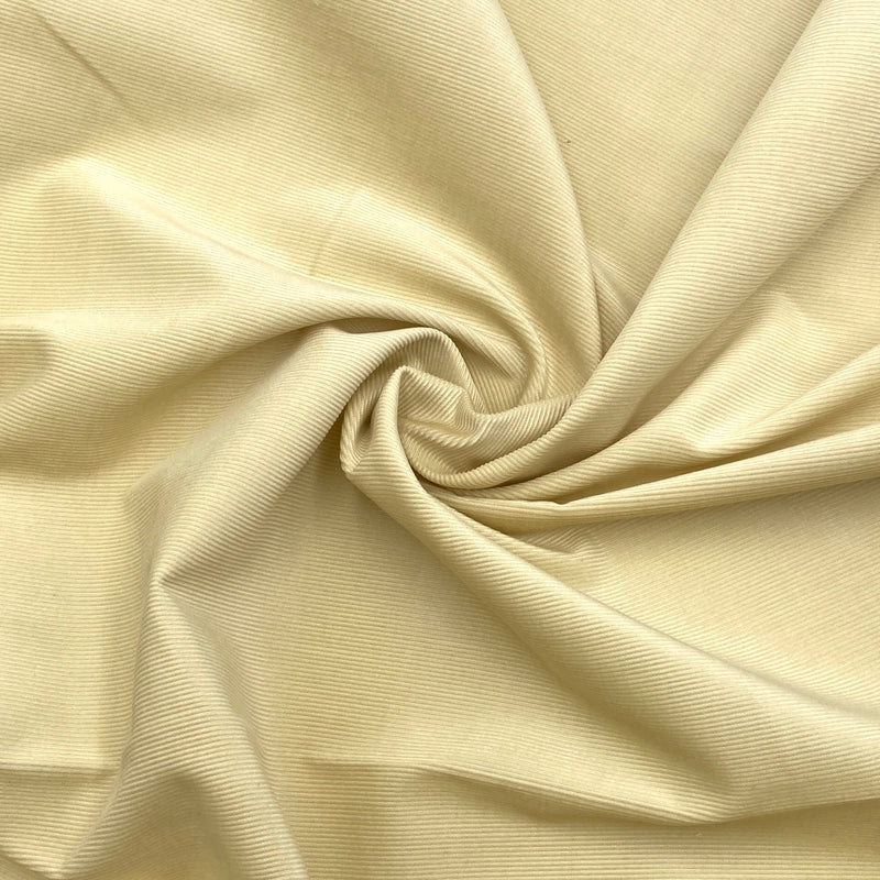 light yellow corduroy fabric scrunched in a swirl to show the texture and thickness