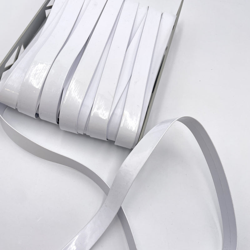 A bolt of bright white faux patent leather trim sitting on a white table.