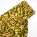 A bolt of green and yellow floral fabric with a batik style print.