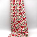 A bolt of ivory fabric with red and pink ornaments and mistletoe printed on it.