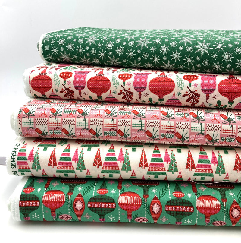A stack of holiday motif quilting cotton fabrics in front of a white backdrop.