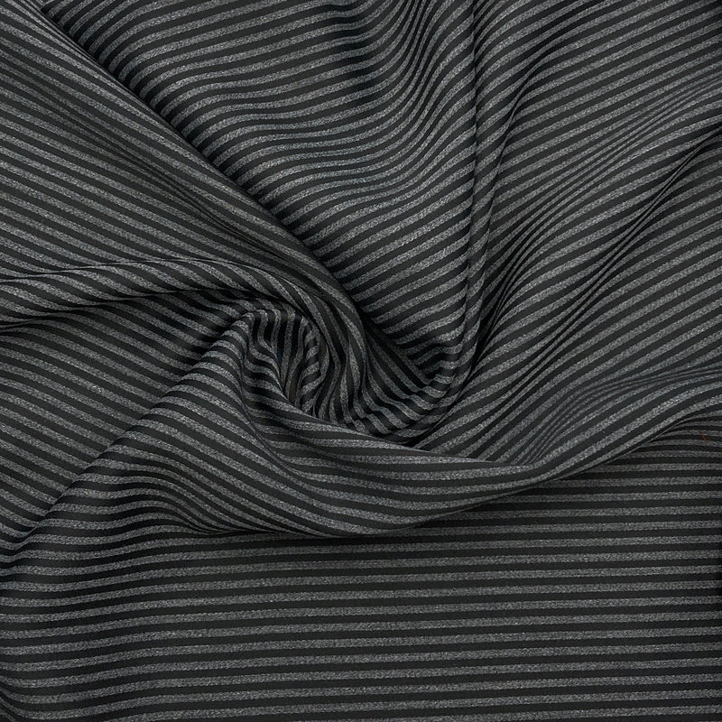 A black and charcoal grey striped fabric scrunched up in a swirl design to show the fabric's texture.