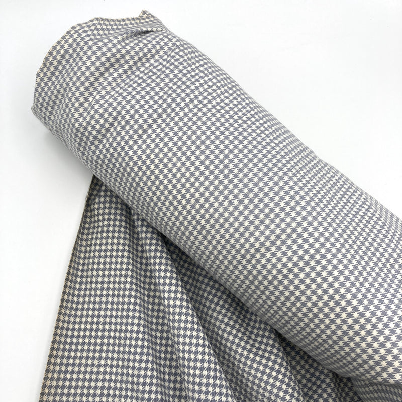 a roll of gray and white corduroy fabric with a houndstooth pattern