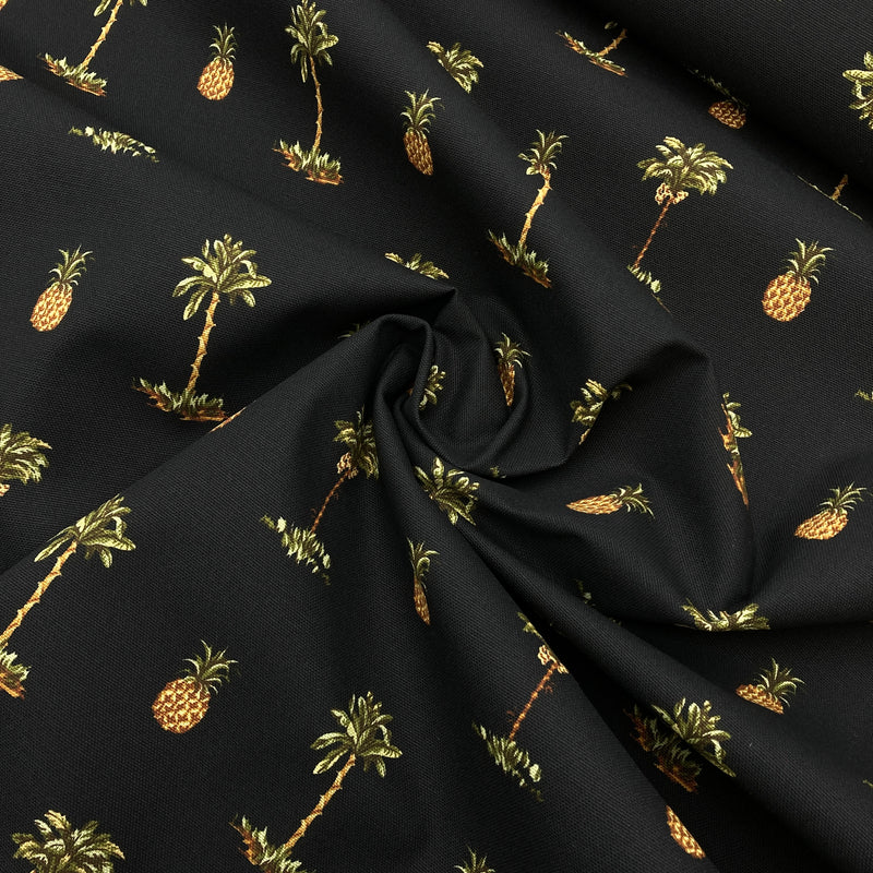 Black canvas fabric with pineapple and palm tree motifs printed on it.