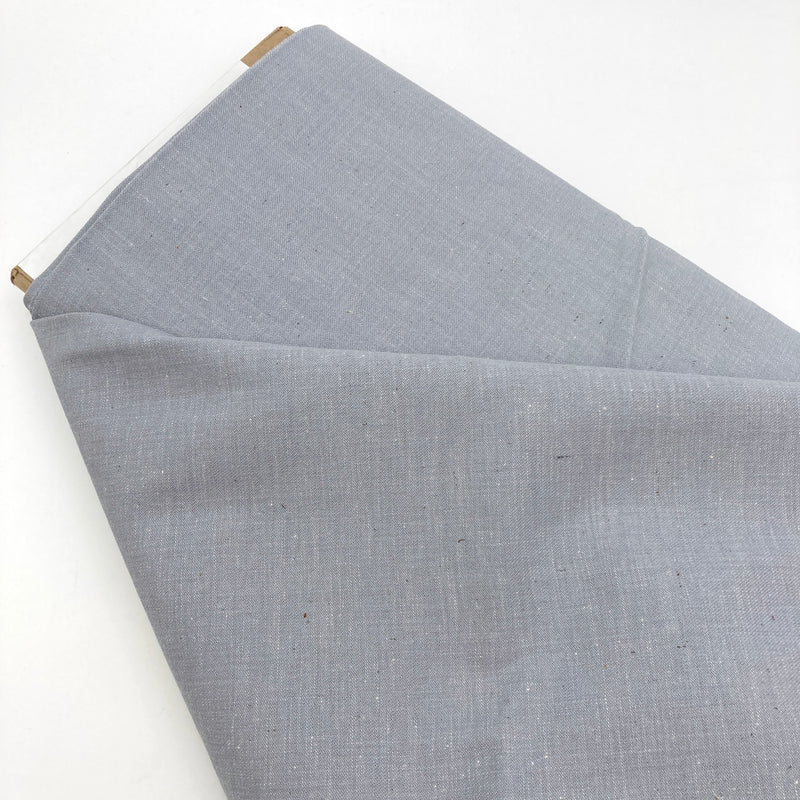 a bolt of blue-grey fabric laying on a white table