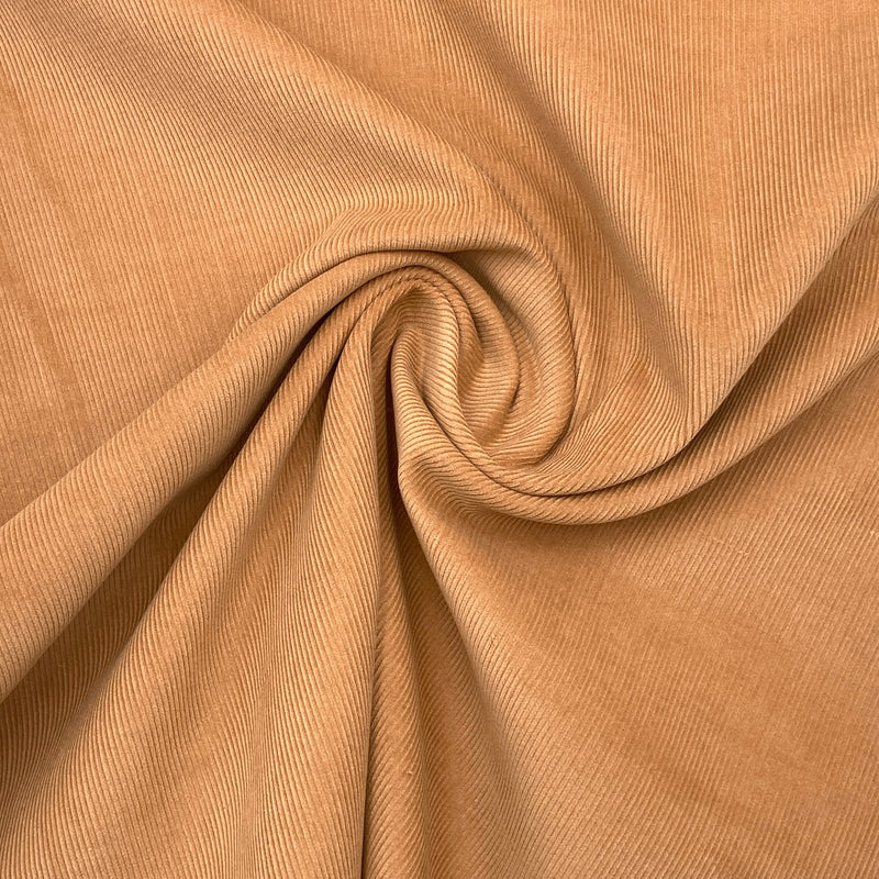 A golden brown corduroy fabric scrunched in a swirl pattern to show its texture and thickness. 