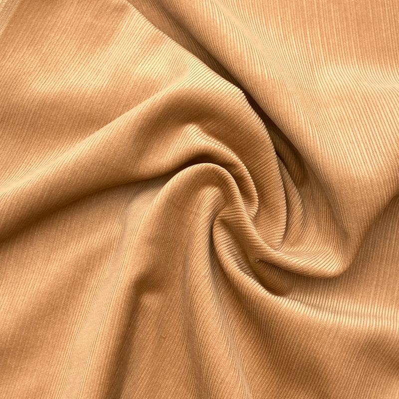 a light brown corduroy fabric scrunched up in a swirl to show the texture and thickness