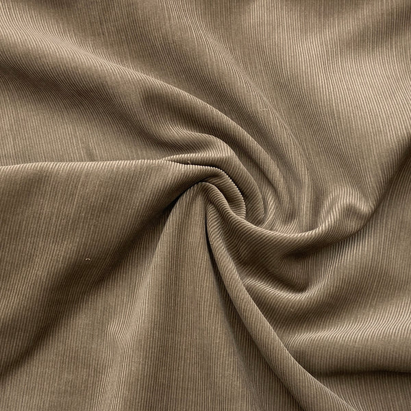 A greyish brown corduroy fabric is scrunched in a swirl pattern to better show its thickness and texture. 