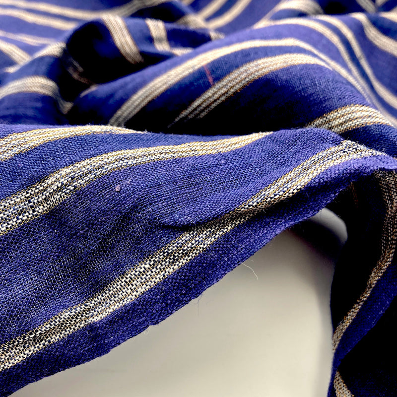 A close-up of linen fabric in a navy blue color with metallic gold and white stripes.
