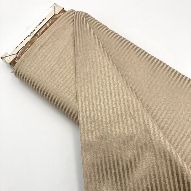 A bolt of tan fabric with stripes made from switching between twill and satin weave.