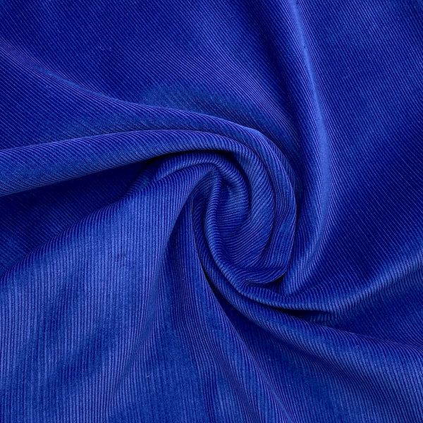 bright cobalt blue corduroy fabric scrunched in a swirl to show the texture and thickness of the fabric