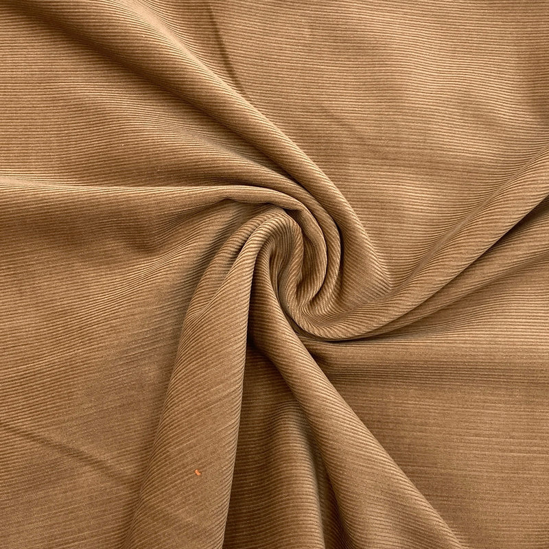 light brown corduroy fabric laid on a table and scrunched into a swirl to show the fabric texture