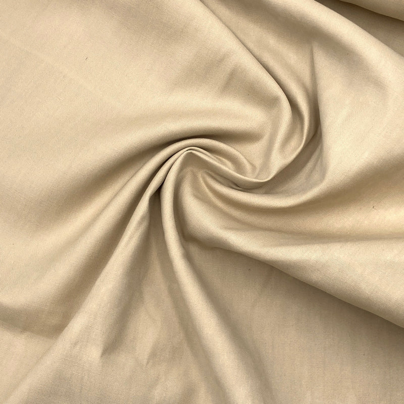 a light beige or tan colored fabric scrunched up in a swirl to show the texture and thickness
