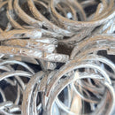 A pile of silver filigree rings designed for use as table sprinkles or favors.